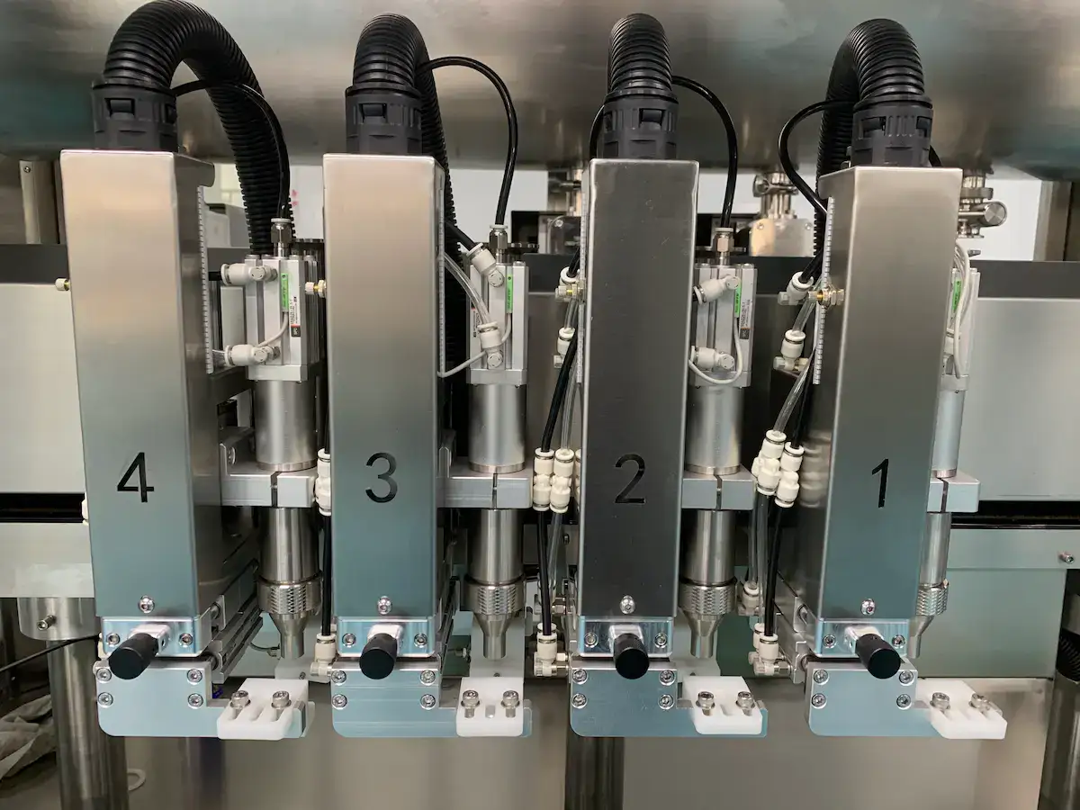 Detalhes ampliados do cabeçote de enchimento da máquina de envase de líquidos.